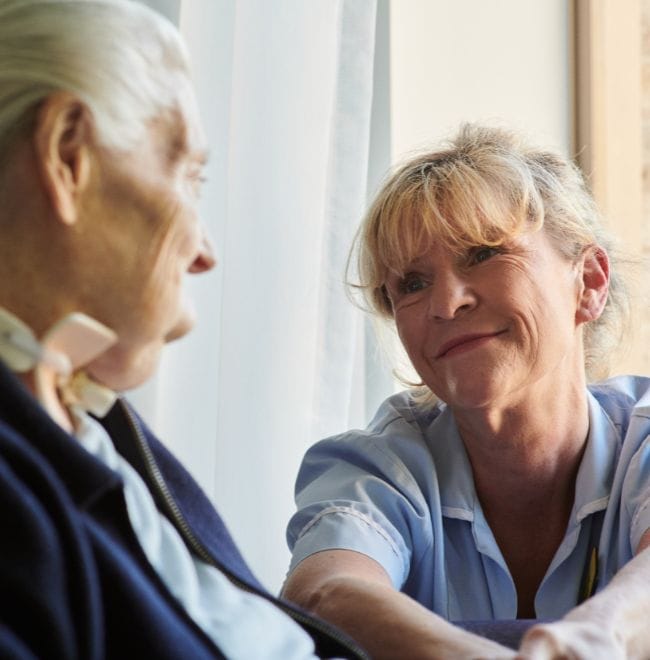 A patient being cared for by a nurse, smiling.