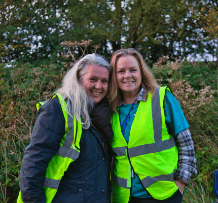 Two people smiling with their arms around each other